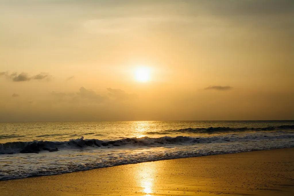 Late sun over the sea, with a gentle wave running up wet golden sand